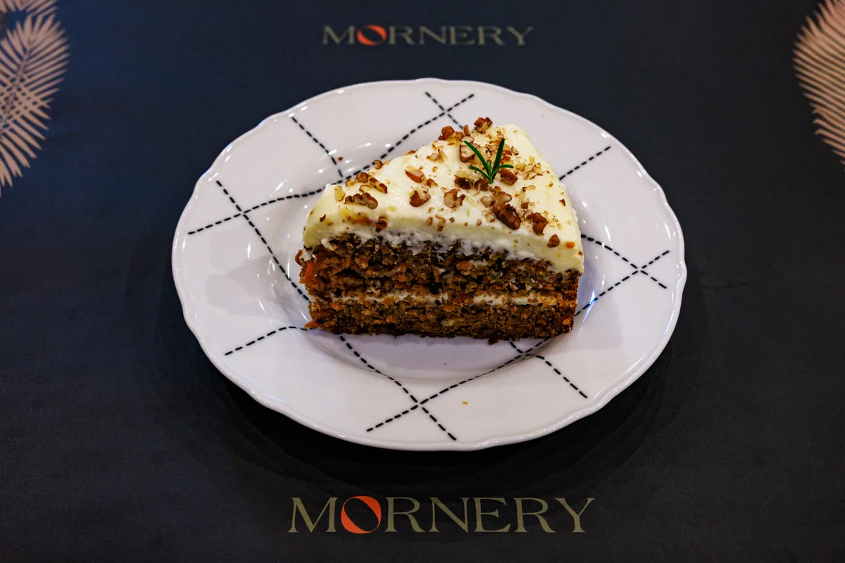 A slice of Mornery carrot cake on a branded plate